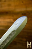 Close-up of a blade with engraved design on a wooden background
