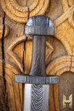 Decorative sword with detailed hilt against a wooden background