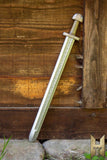 Decorative sword with ornate handle against a wooden background