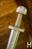 Decorative sword with gold hilt and blade on a wooden background
