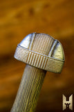 Close-up of a decorative sword hilt with intricate patterns on a wooden background