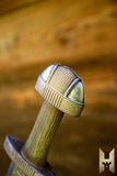 Close-up of a sword hilt with intricate design on a wooden background