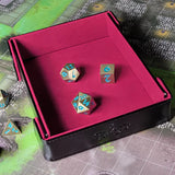 A red and black dice tray with a game board in the background.