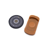 Round black object with circular design and a brown rectangular object on a white background