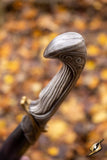 Decorative walking cane with intricate design against a blurred autumn leaf background
