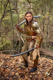 Person in fantasy costume with swords in a forest setting