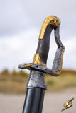Decorative sword hilt with gold and silver details on a blurred natural background