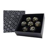 Set of metallic dice with gold and silver accents in a black box with geometric pattern