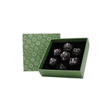 Set of crystal dice in a green box with geometric pattern