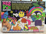 The back of the retail box for the Needoh Advent Calendar, featuring colorful retro illustrations, product description text, and a hand demonstrating the included finger puppet.