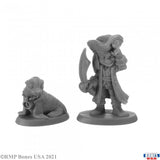 Two gray miniature figures on a white background, one resembling a dog and the other a person with a hat and coat.