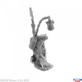 Gray miniature figurine of a skeleton with a lantern on a white background