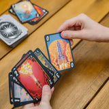 Hand holding tarot cards with rocket design on a wooden surface