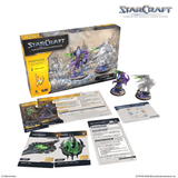 StarCraft tabletop miniature game box and contents arranged on a white background, including the main box, two miniatures, cards, and rules sheets. The StarCraft logo is visible at the top right.