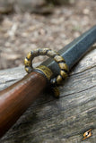 Close-up of a sword with a decorative hilt on a wooden surface