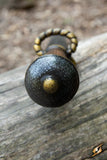 Close-up of a black and gold weapon handle on a wooden surface