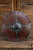 Wooden shield with metal boss and rings on a wooden background