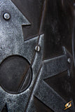 Close-up of a detailed metallic armor piece with rivets and geometric patterns.