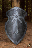 Decorative metal shield with a cross design on a forest floor background