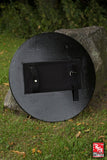 Round black fire pit on a grassy area with a blurred background