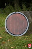 Wooden round shield on a grassy background with a tree trunk