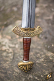 Decorative sword hilt with intricate designs on a stone surface