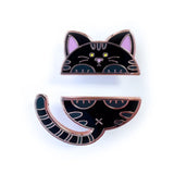 A two-piece cat-themed enamel pin set on a white background. The top piece shows a black cat head with pink inner ears, yellow eyes, and white whiskers.