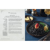 Squid ink pasta with scallops on a plate next to a recipe card.