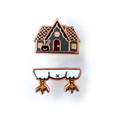 Enamel pin of a small house with chicken feet on a white background