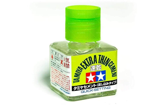 Bottle of Tamiya Extra Thin Cement with green cap on a white background