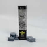 Set of dark gray candles with packaging labeled 'The Glowing City' on a light gray background