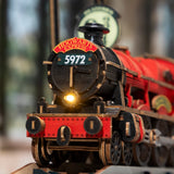 A close-up of a decorative model steam locomotive with a red body, black front cab, illuminated headlight, and the front plaque reading 'Hogwarts Express' and number '5972'.