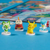 Four colorful figurines on a blue surface with a board game in the background