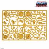 Gold toy battle mat with character figures on a white background, featuring 'Masters of the Universe Battleground' branding.
