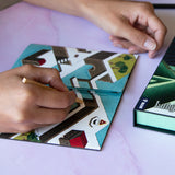 Hands playing with geometric tile pieces on a light purple surface