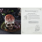Decorative skull with pink brain and grapes on a dark surface, next to a recipe card.