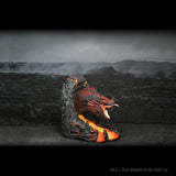 Dragon figurine on a rocky outcrop with a dark, mountainous landscape in the background