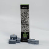 A boxed candle set labeled 'The Cryptid Cabin' by Cantrip Candles, shown with four small tealight candles in a dark gray color arranged around the tall product box on a light gray studio background.
