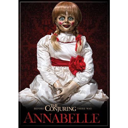 Horror doll in a white dress with red accents against a dark background, featuring text about 'The Conjuring' and 'Annabelle'.