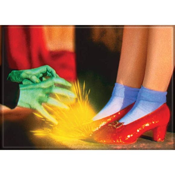 Red shoes with blue socks stepping onto a green hand with yellow sparkles, against a red curtain background.