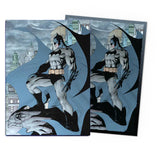 Two Batman comic book covers with a cityscape background