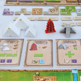 Board game setup with pyramid-themed cards and pieces on a white surface