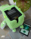 Green plush toy with card holder on a tiled floor, featuring 'Magic: The Gathering' branding.