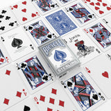 A boxed deck of Bicycle Sterling playing cards arranged on a white surface with several illustrated playing cards spread around it. The box shows the classic blue spade logo and the word 'Sterling,' and multiple cards display red and black court and suit designs on white backgrounds.