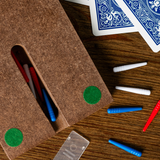 Brown felt pouch with green dots on a wooden surface with playing cards and markers.