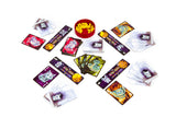 A spread of cards, tokens, and a small red bowl filled with yellow pieces on a plain white background. The cards feature illustrated cat characters in various colors, including purple, orange, green, and red, with some cards showing white backs.