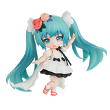 Anime character figurine with turquoise hair and a white dress on a white background