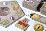 Board game components including cards and a die on a white surface