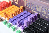 Board game components including purple tokens, dice, and a box labeled 'Taband' on a white background.