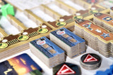 Close-up of board game components including cards and tokens on a wooden board.